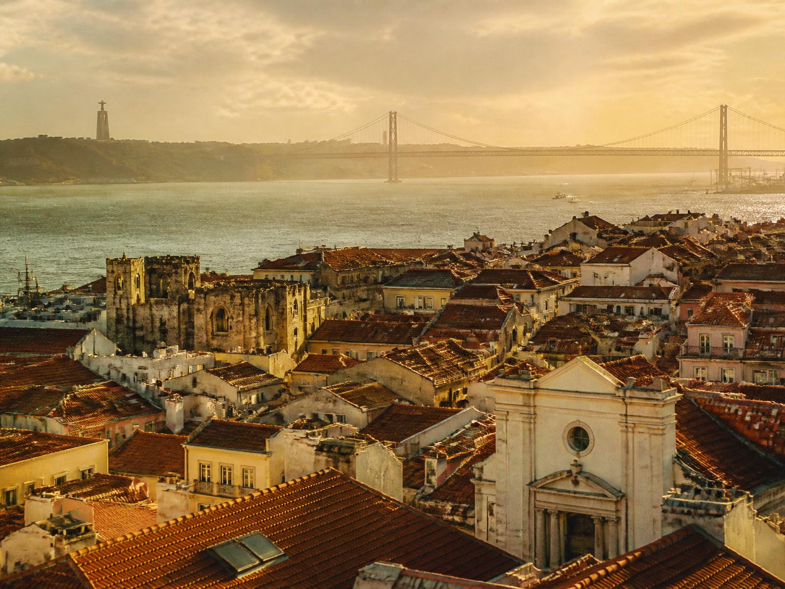 Lisbon rooftops at golden hour with the 25 de Abril bridge in the distance